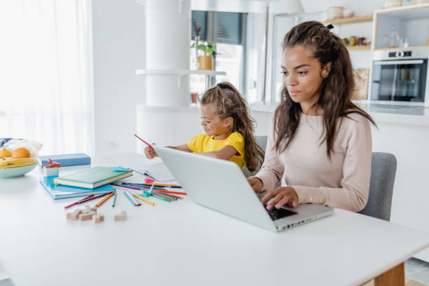 istock Young mother is working from home and her daughter is writing homework next to her 1370967732