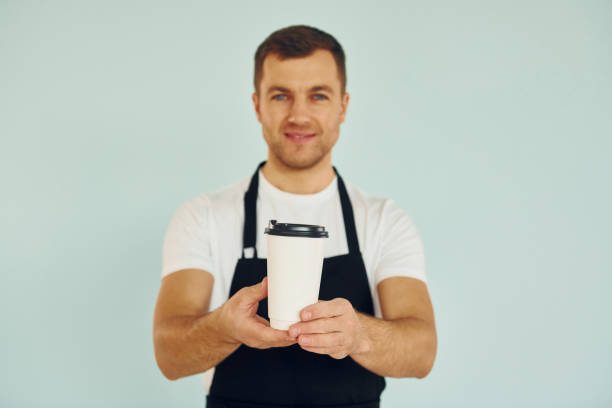 istock Man in uniform standing in the studio with drink in hands 1370969078