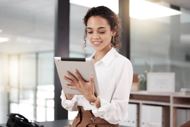 istock Shot of a young businesswoman using a digital tablet while standing in her office 1370972090