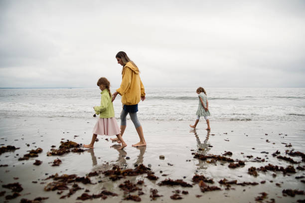 istock Mother and daugthers walking on a beach. 1370973021