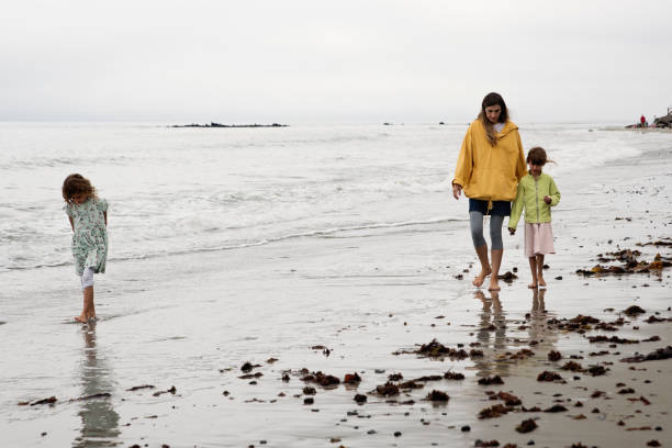 istock Mother and daugthers walking on a beach. 1370973113