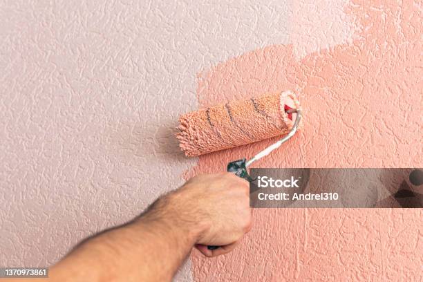 Mans Hand Paints The Wall With A Paint Roller In Pink Stock Photo - Download Image Now