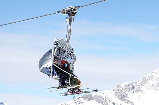 Skiiers with facemasks on, in a chairlift in the skiresort of St. Anton am Arlberg on a sunny day in Austria. It is now allowed to go skiing if you are vaccinated and wear a FFP2 mask in lifts and buses.