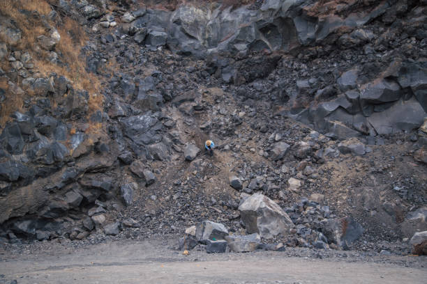 istock man breaking volcanic rock with metal hammer 1370974915