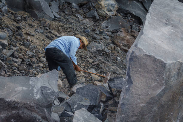 istock man breaking volcanic rock with metal hammer 1370975219