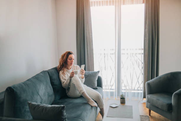 istock woman relaxing on her sofa at home using smart phone and drinking a coffee 1370976184