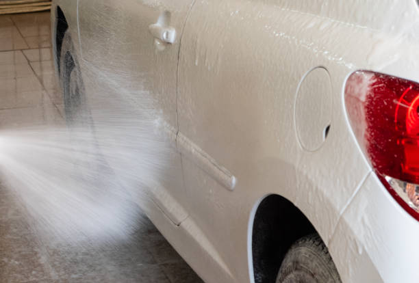 istock Powerful jet of white foam applied on white car in open garage 1370978134