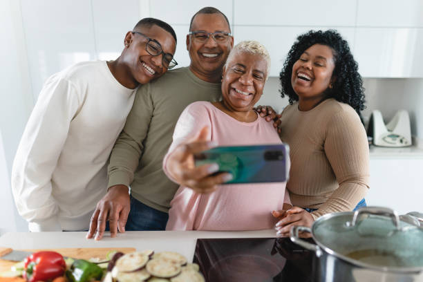 istock Happy Latin family having fun taking selfie with mobile smartphone while preparing healthy lunch in modern kitchen at home - Food and parents concept 1370978176