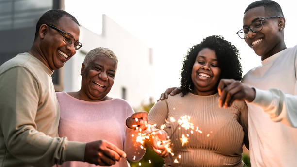 Happy African family celebrating holidays with sparklers fireworks at house party stock photo