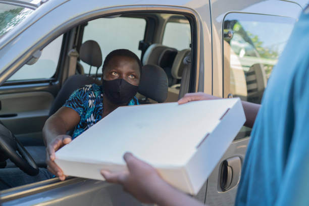 istock Black customer wearing protective face mask receiving  package on car 1370981013