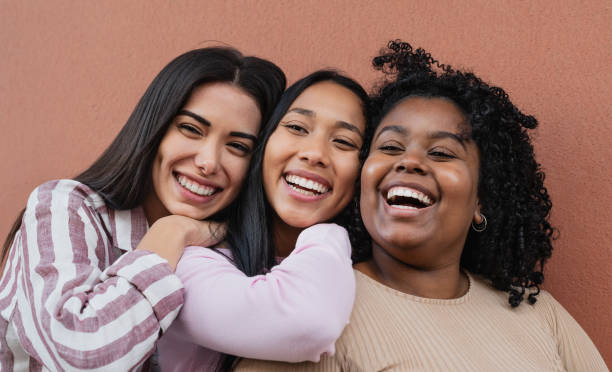portrait of happy multiracial friends embracing and smiling in front of camera - girl woman imagens e fotografias de stock