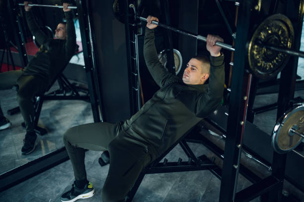 istock Man training in the gym while lifting barbell 1370984393