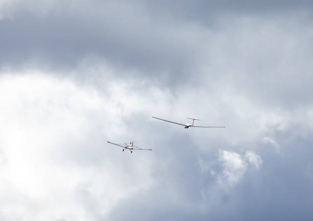 A distant paraglider navigating through the sky surrounded by layers of white clouds.