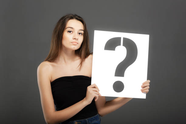istock brunette girl holding a question mark sign 1370993617