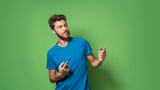 Bearded guy isolated on a green background pointing fingers to an empty space stock photo