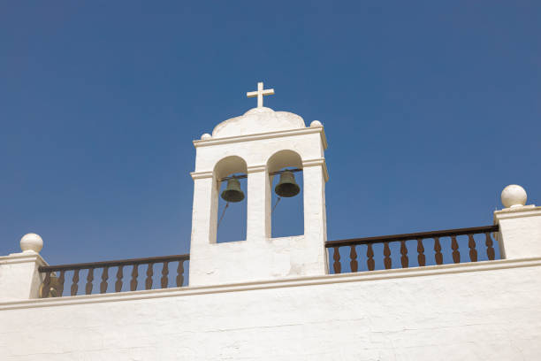 White bell tower of a church over blue sky.