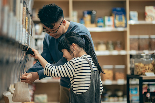 Asian father and daughter come to buy in eco-friendly store, education concept