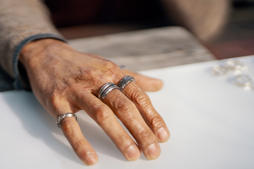 Various silver rings on a silversmith`s hand while he is working
