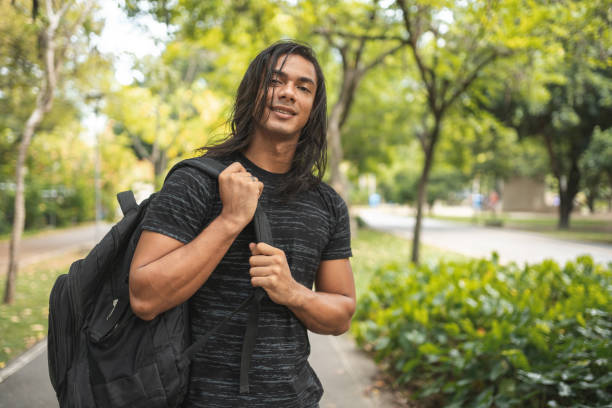 Indigenous man carrying a backpack in the public park Indigenous, Man, Carrying, Backpack, Public park gay long hair stock pictures, royalty-free photos & images