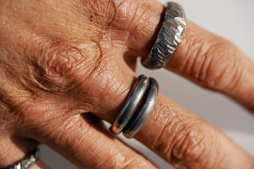 Various silver rings on a silversmith`s hand while he is working