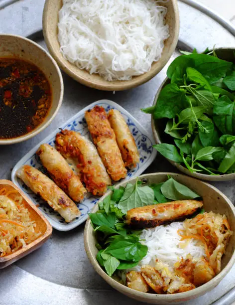 Top view tray of Vietnamese food for daily family meal weekend, fried spring roll rice noodles with lettuce and basil leaf and soy sauce, vegan dish good for healthy by non meat menu