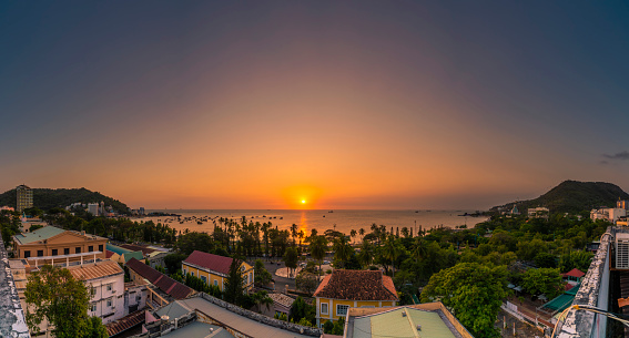 Panoramic coastal Vung Tau view from above, with waves, coastline, streets, coconut trees and Tao Phung mountain in Vietnam. Beautiful sunset on the sea. Travel and landscape concept