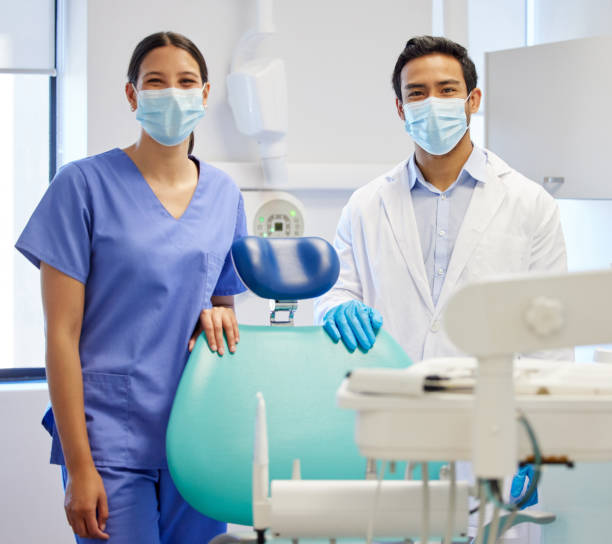 портрет молодого стоматолога и его помощника, работающих в их консультационной комнате - зубной ассистент стоковые фото и изображения