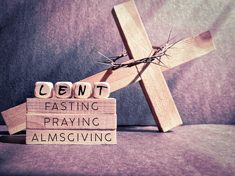 Words ' lent fasting praying almsgiving' on wooden blocks in purple vintage background. Stock photo.