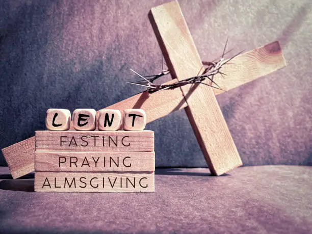 Words ' lent fasting praying almsgiving' on wooden blocks in purple vintage background. Stock photo.