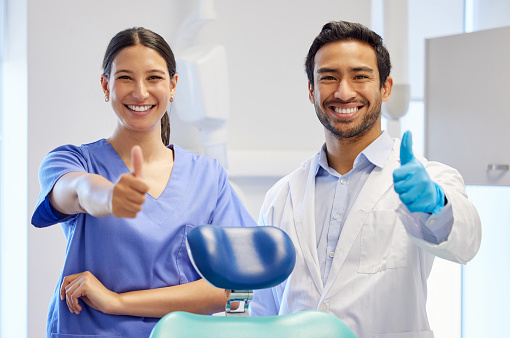 Retrato de dos jóvenes dentistas con el pulgar hacia arriba en su consulta photo