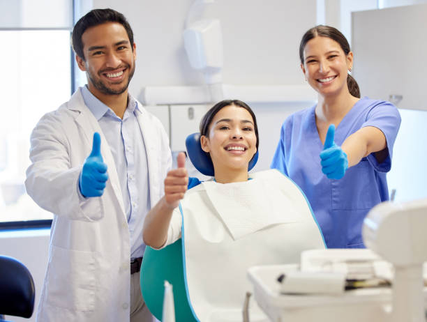 歯医者を訪れている間に親指を立てている若い女性の肖像画 - dental assistent ストックフォトと画像