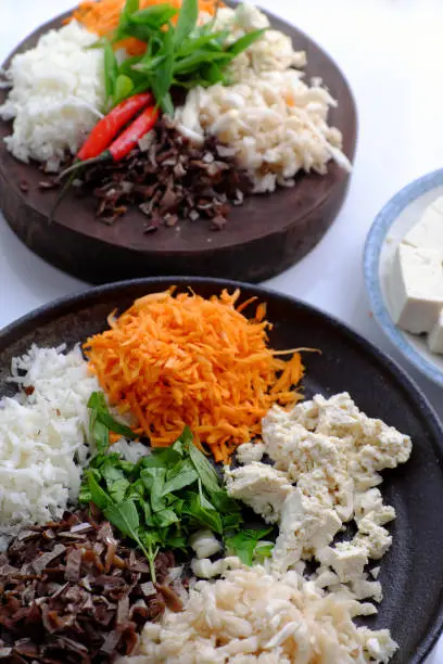 Top view raw material ready to cook homemade rice noodles roll, vegan ingredient as wood ear mushroom, carrot, rice batter, tofu that chopped on white background, Vietnamese popular dish