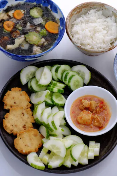Top view vegan daily meal for lunch, cucumber slice with tofu cheese, seaweed soup, rice bowl, simple vegetarian Vietnamese food that nutrition and good for health on white