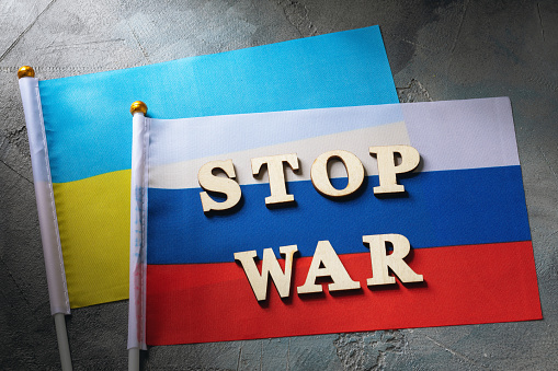 Text from wooden letters and two flags  on an abstract background, the concept of preventing war between Russia and Ukraine