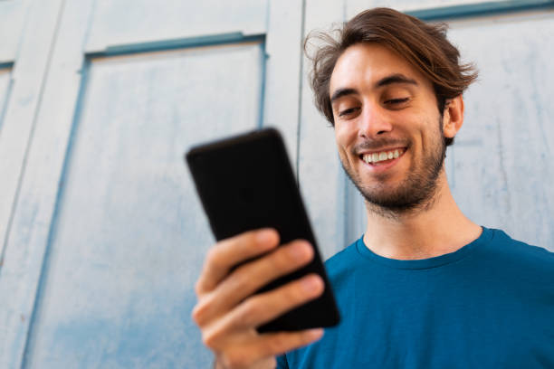 istock Close up portrait of smiling young caucasian man using mobile phone outdoors. Copy space. Selective focus on face 1371017917