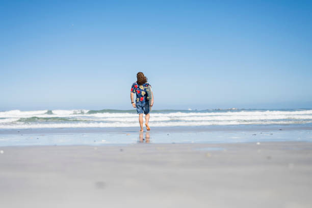 Surfer staring at the ocean with board next to him