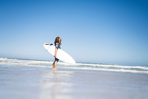 Surfer standing in shallow water looking for waves