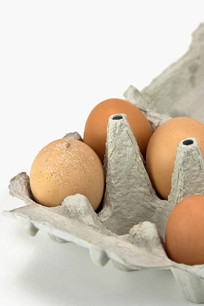 close-up de um eggbox e quatro ovos - cholesterol ellipse shell box - fotografias e filmes do acervo