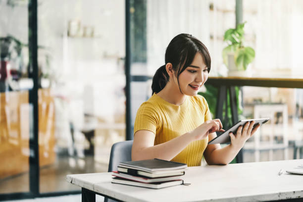 istock Young female student sitting at a desk using a tablet when studying with a video conferencing system. 1371023375
