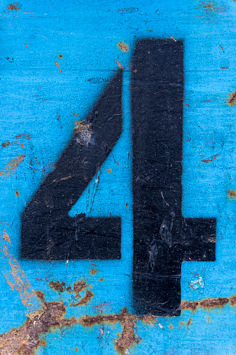 Number 4 in black paint on an old blue iron surface with rust texture and traces of dirt. High quality photo