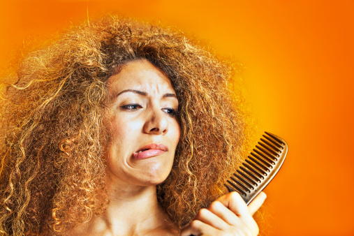 Women with messy hair looking at her hairbrush.