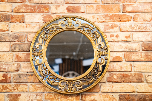 Beautiful round mirror with pattern on a metal frame on a brick wall. decorative elements for home and interior.