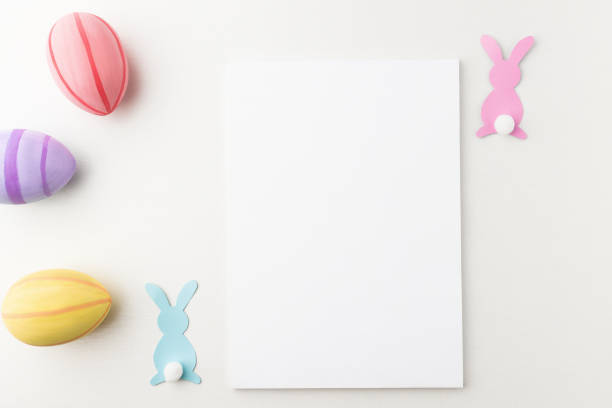 istock Easter card with white empty copy space template with colorful eggs and paper figurines of rabbits on white background, flat lay. 1371035817