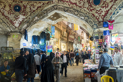 Tehran, Iran - October 31, 2016: Shoppers and traders walking past market stalls through a busy Grand Bazaar in Tehran, Iran