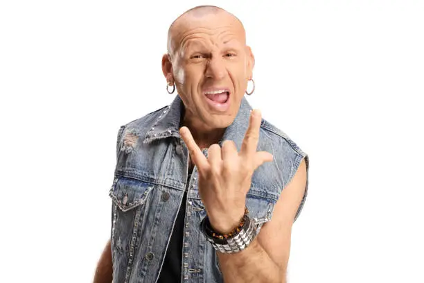 Bald rocker man in a denim vest posing and gesturing rock and roll sign isolated on white background