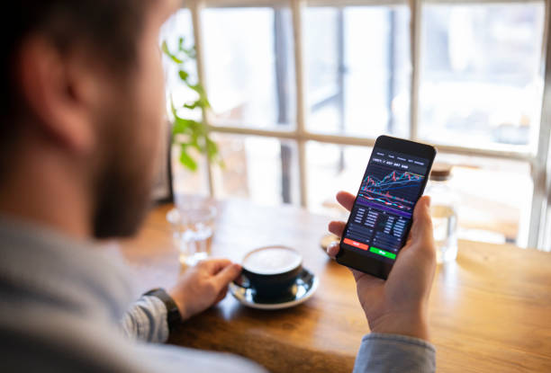 istock Young man using stock trading app on smart phone. 1371039120