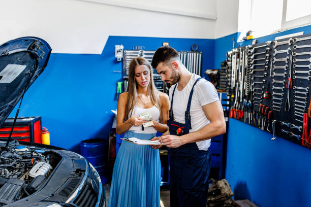 若い女性が現金で彼の車の修理を支払っています。 - coveralls professional occupation manual worker service occupation ストックフォトと画像
