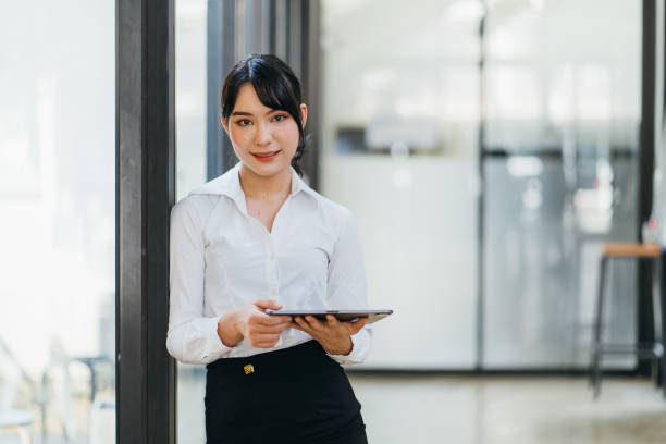 istock Happy woman manager holding touch pad and thinking about something good while standing in modern office interior,young smart female secretary smiling for someone during work on portable digital tablet 1371043075