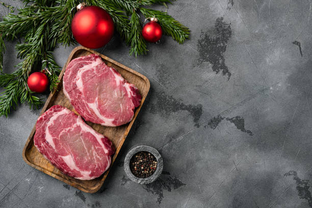 filete fresco de rib-eye crudo con un árbol de navidad, sobre fondo de mesa de piedra gris, vista superior plana, con espacio de copia para texto - steak strip steak ribeye sirloin steak fotografías e imágenes de stock