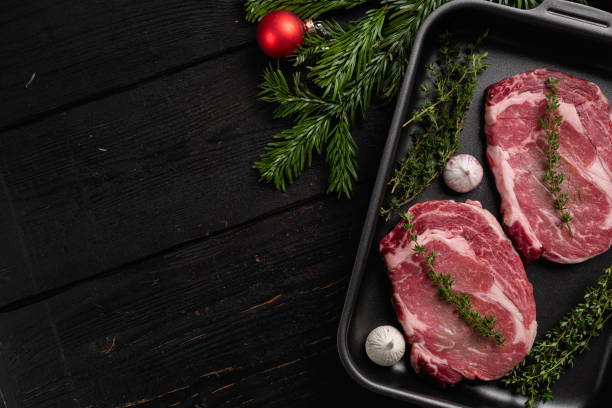 clásico filete de rib eye fresco con decoraciones de árbol de navidad, sobre fondo de mesa de madera negra, vista superior plana, con espacio de copia para texto - steak strip steak ribeye sirloin steak fotografías e imágenes de stock